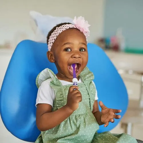 Young child brushing teeth in dental chair
